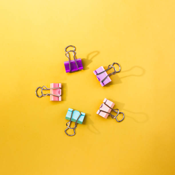 istock Colorful paper clips on a yellow backdrop 1287497136