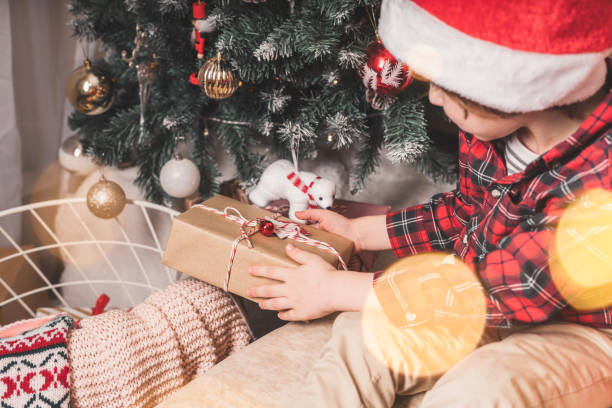 istock Close-up of child hands put gift under a Christmas tree. 1287497348
