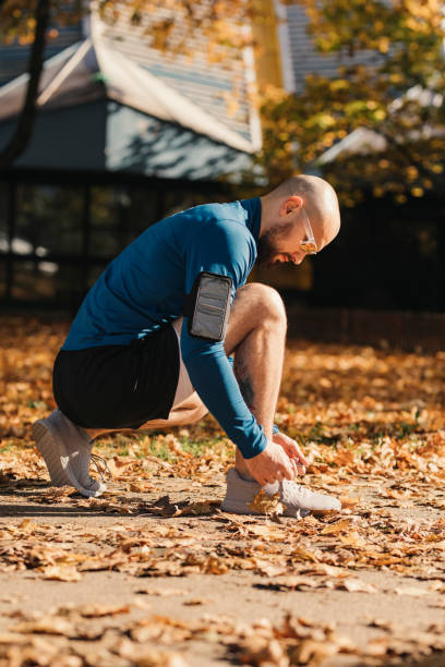 istock Handsome Young Man in a Public Park, Making a Short Break from Exercising to Tie his Shoelace 1287497762