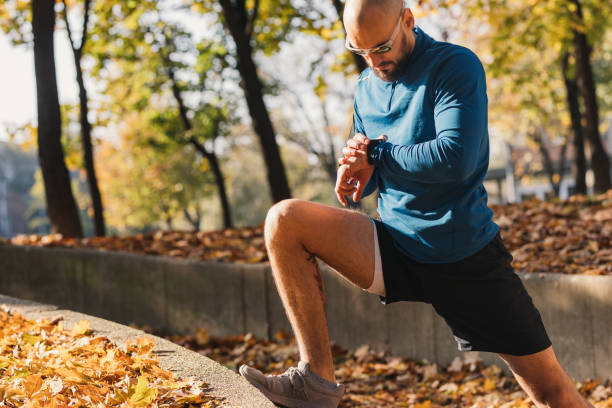 Fit Male Athlete Stretching after a Good Outdoors Workout and Checking his Pulse on his Smartwatch
