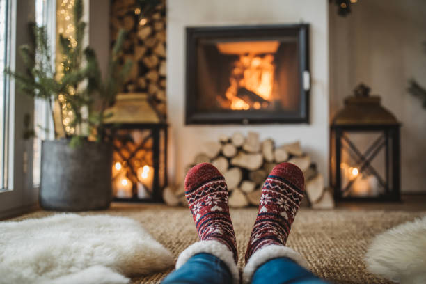 Winter day by fireplace Lazy winter day in front of fire in fireplace. Human legs in socks in front of fireplace. heat home interior comfortable human foot stock pictures, royalty-free photos & images