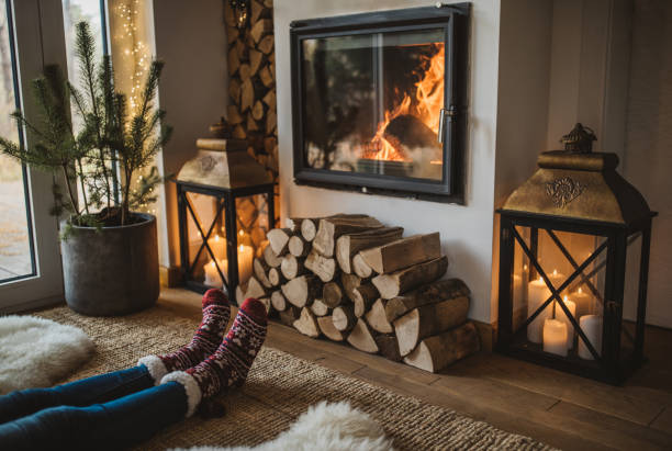 Winter day by fireplace Lazy winter day in front of fire in fireplace. Human legs in socks in front of fireplace. cottage life stock pictures, royalty-free photos & images