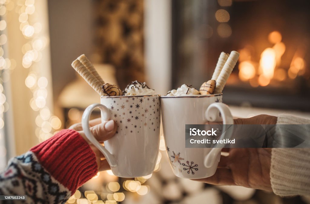 Winter day by fireplace Lazy winter day in front of fire in fireplace. Woman and man hands with a cup of hot chocolate. Hot Chocolate Stock Photo