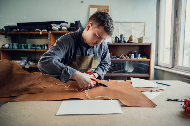 istock A young tanner in his workshop at the table cuts out leather elements of shoes 1287504189