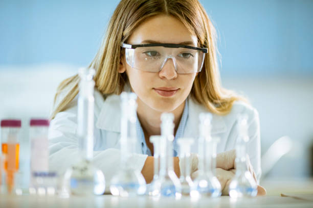 istock Female medical or scientific researcher looking at a flasks with solutions in a laboratory 1287509093