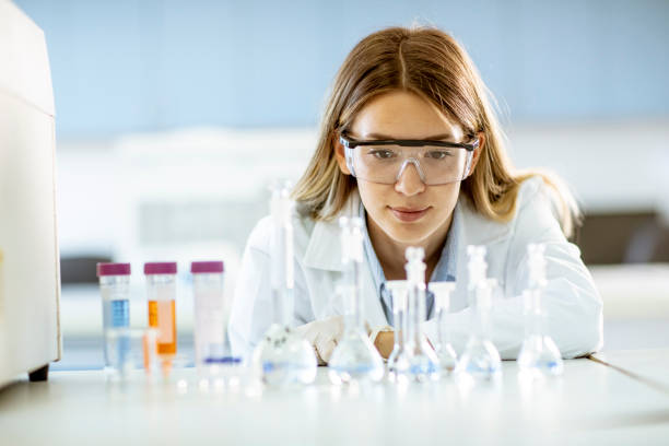istock Female medical or scientific researcher looking at a flasks with solutions in a laboratory 1287509098