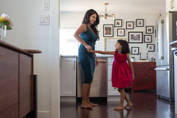 istock Mother and elementary age daughter dancing together at home 1287510131