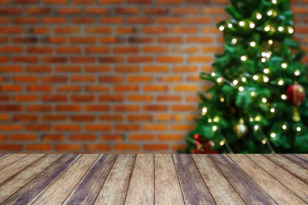 istock Empty wood table top with blur decorated Christmas tree with baubles on brick wall background 1287510318