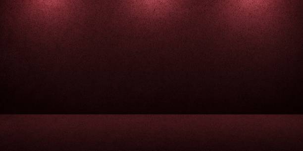 istock Empty burgundy plastered wall lit by dim ceiling lights, studio room to display your products. Background from floor and wall. 1287510505