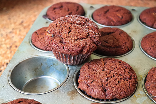 A chocolate zucchini muffin pulled out of a tray.