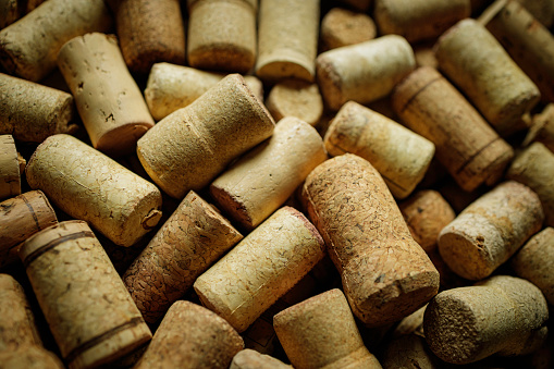 Old corkscrew and broken cork on a gray background. The corkscrew lies next to a broken wine cork. Selective focus