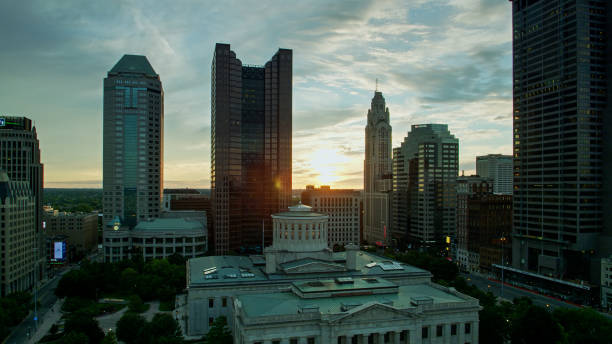 Sun Setting Behind Ohio Statehouse and Downtown Columbus Skyline Aerial establishing shot of the Ohio Statehouse in Columbus at sunset. ohio ohio statehouse columbus state capitol building stock pictures, royalty-free photos & images