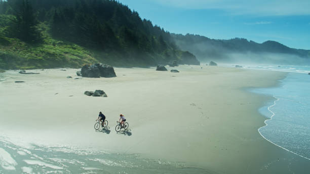 istock Friends Riding Bikes Side by Side on Whaleshead Beach, Oregon - Aerial 1287527193