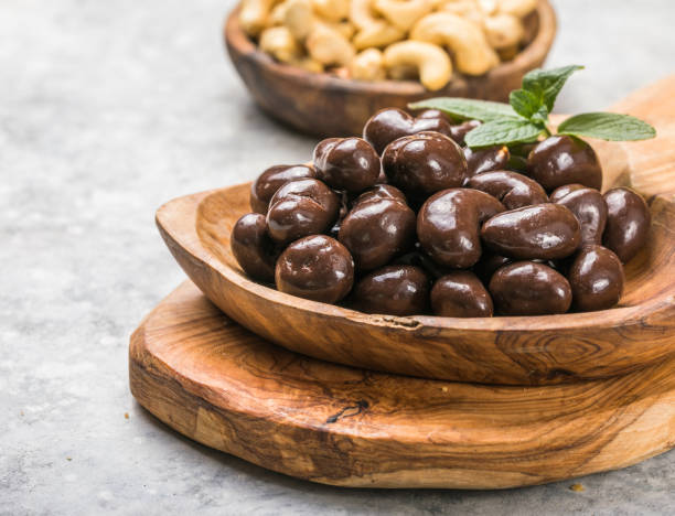 sweet cashew and chocolate covered nuts on gray stone background.