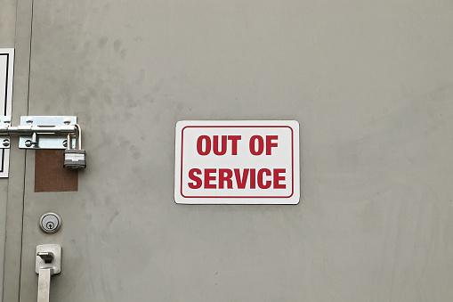 A white Out of Service Sign on a locked door.