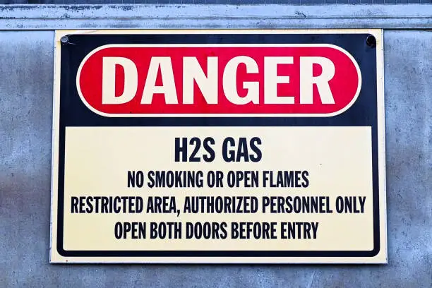 Closeup of a white Danger H2S Gas sign.