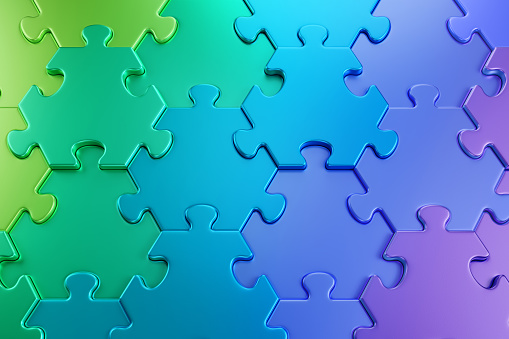 Close-up view of varicoloured hexagonal pieces of a jigsaw puzzle composed to color gradient from green to purple through blue. 3D-rendering graphics.