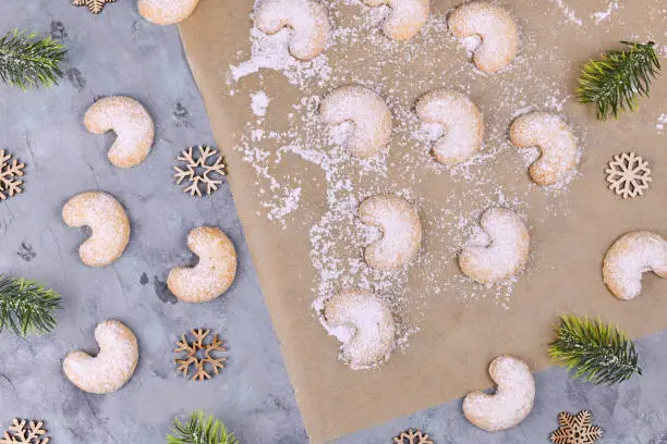 Top view of crescent shaped christmas cookies called 'Vanillekipferl', a traditional Austrian or German Christmas biscuits with nuts and icing sugar surrounded by Christmas decoration