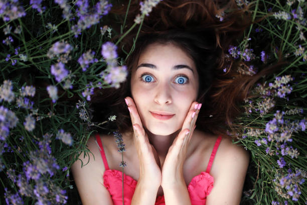 Beautiful young girl with blue eyes laying in lavander field