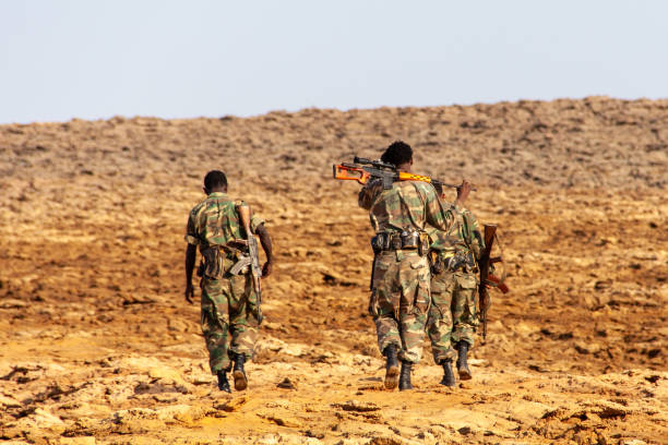 Back view of three Ethiopian soldiers walking in the wasteland Dallol, Ethiopia - Jan 17, 2014: Ethiopian National Defense Force (ENDF) soldiers escort foreigners near the border with Eritrea. Led by the soldiers, we proceeded toward Dallol area. horn of africa photos stock pictures, royalty-free photos & images