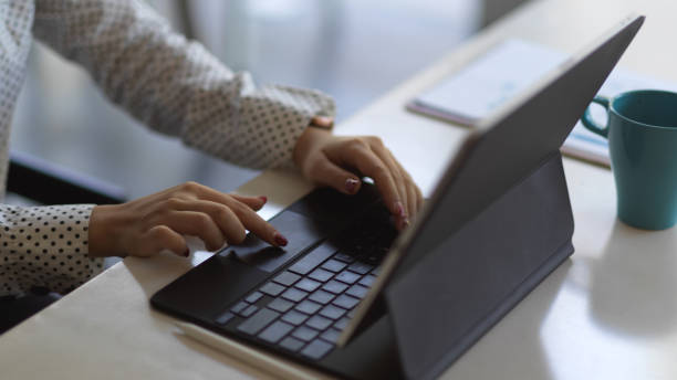 istock Female hands typing on tablet keyboard on white table in office room 1287549469