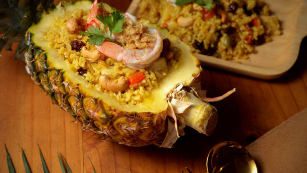 istock Pineapple Fried Rice  (Kao Pad Sapparod) in cutted pineapple bowl on wooden table 1287549567