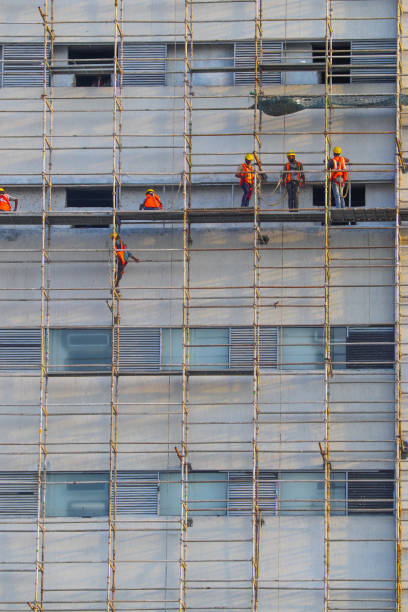 Scaffolding without netting in a construction site, red brick wall, window holes, full frame. apartment building construction site . Full frame view.