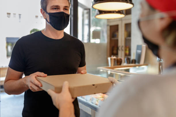 istock Customer wearing protective face mask taking pizza box from employee 1287551842