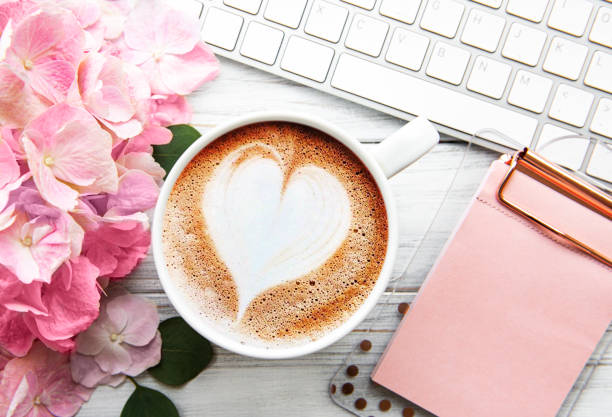 istock Home office desk workspace with pink hydrangea flower bouquet, cup of coffee and keyboard 1287553110