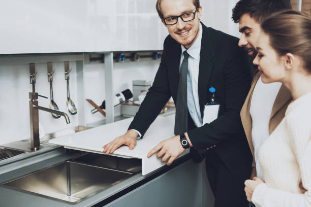 istock Manager is showing kitchen sink with cover to couple clients in kitchen store. 1287555647