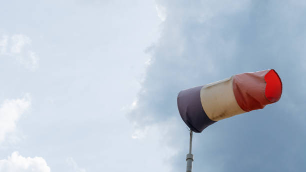 paleta de viento voladora con líneas rojas, blancas y azules sobre un fondo de cielo dramático. pruebe la dirección del viento, los instrumentos de velocidad del viento. espacio para el texto. - windsock sky natural phenomenon gale fotografías e imágenes de stock