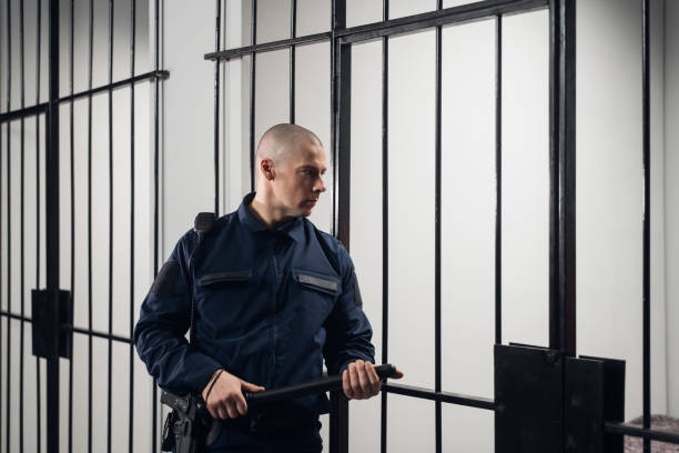 ein strenger gefängniswärter in uniformen wachzellen mit gefangenen in einem hochsicherheitsgefängnis - detention center stock-fotos und bilder