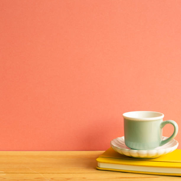 istock Coffee cup with notebook on wooden table. Pink background 1287563196