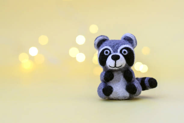 istock Toy wool raccoon on a yellow background with bokeh 1287563427