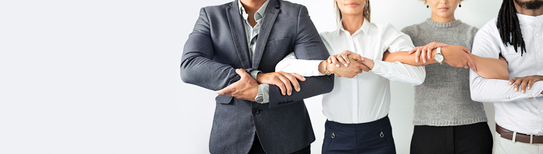 Closeup shot of a group of unrecognisable businesspeople standing together with their arms linked into each other