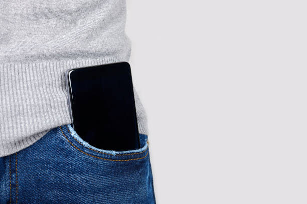 istock Mobile phone in jeans pocket on grey background. 1287568378