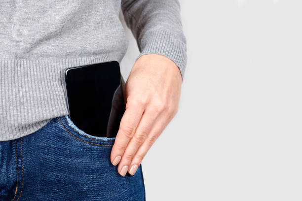 istock Hand with mobile phone in jeans pocket on grey background. 1287568384