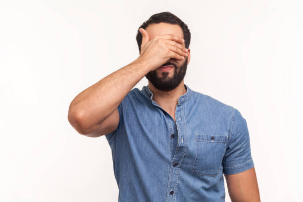 istock Bearded man in blue shirt closing eyes with hand, dont want to see that, ignoring problems, hiding from stressful situations 1287568493