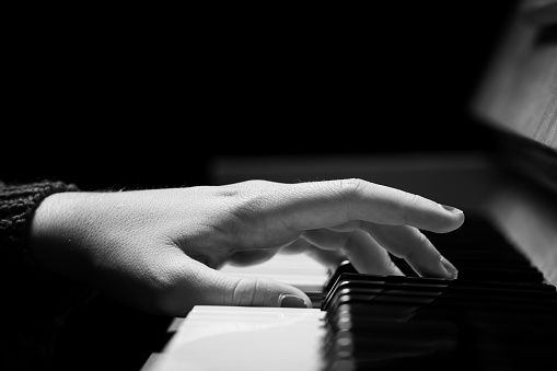 Hand of a girl with colored finger nails playing the piano