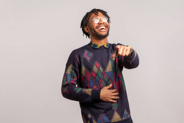 positivo excitado hombre africano con rastas en gafas riendo en voz alta sosteniendo el vientre y señalando con el dedo en ti, burla - haciendo burla fotografías e imágenes de stock