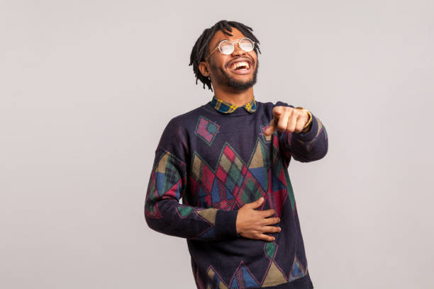 Positive excited african man with dreadlocks in eyeglasses laughing out loud holding belly and pointing finger on you, mockery Positive excited african man with dreadlocks in eyeglasses laughing out loud holding belly and pointing finger on you, mockery. Indoor studio shot isolated on gray background teasing stock pictures, royalty-free photos & images