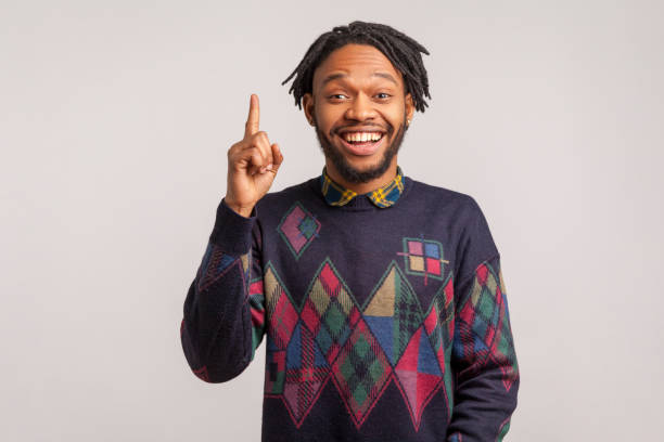 istock Extremely happy african guy with dreadlocks in stylish sweatshirt pointing finger up with toothy smile on face, clever smart man has idea, start up 1287568765