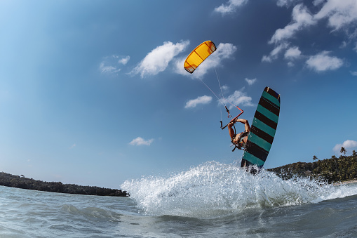 A young man kiteboarder scrapes the water with his hand inside