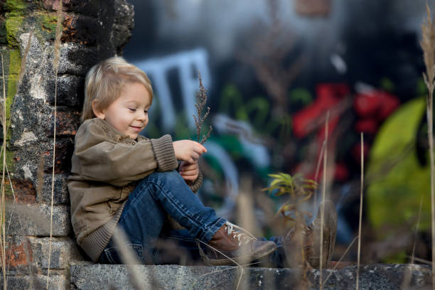 słodkie dziecko, pozowanie w ruinie domu z cegły, siedząc na tarczy okna, jesień - child graffiti grunge city zdjęcia i obrazy z banku zdjęć