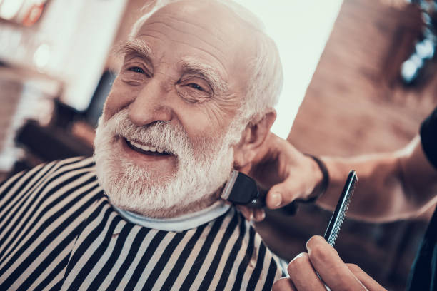 Grey Haired Adult Smiles During Nape Haircutting. stock photo