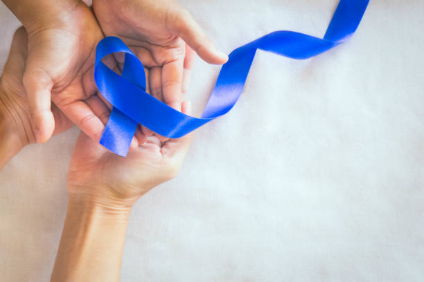 istock Hands holding deep blue ribbon on white fabric with copy space. Colorectal Cancer Awareness, Colon cancer of older person and world diabetes day, Child abuse prevention. Healthcare, insurance concept. 1287571445