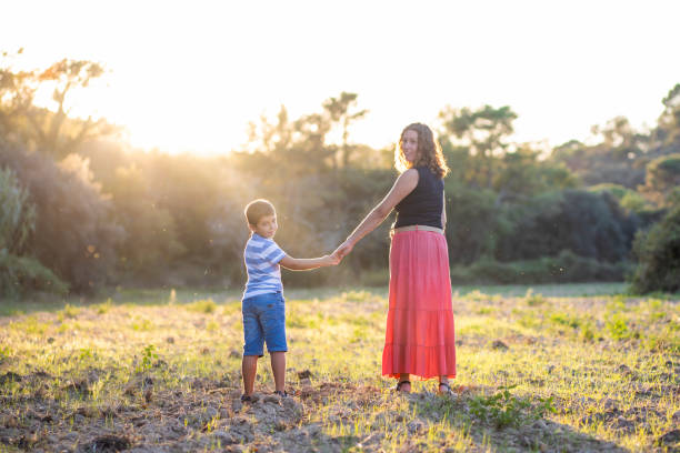 istock Woman and kid holding hands on a meadow 1287571449