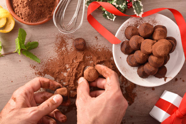 Hands putting cocoa into homemade truffles for an event top hands putting cocoa into homemade truffles for an event. Top view. Horizontal composition. chocolate truffle making stock pictures, royalty-free photos & images