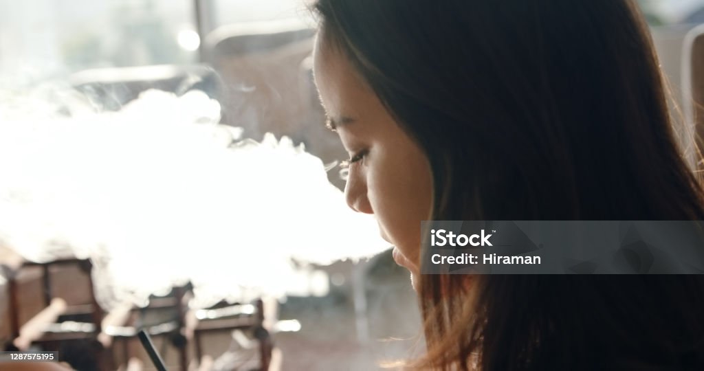Keeping it cloudy in quarantine Shot of a young woman vaping at home Electronic Cigarette Stock Photo