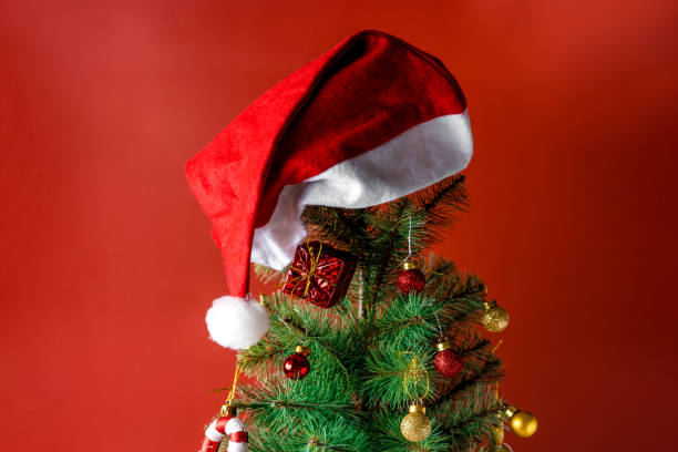istock Christmas tree with a hat on top, white lantern on a red background 1287577604
